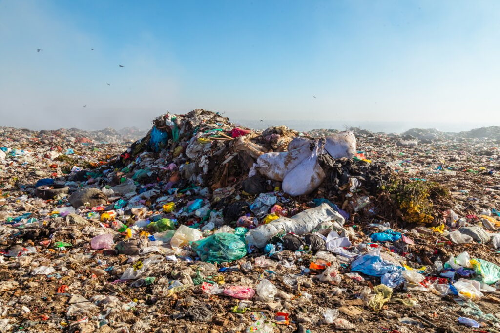 Closeup of burning trash piles in landfill with flying crows over the site